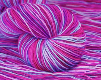 May include: A close-up of a skein of yarn in shades of pink, purple, and light blue. The yarn is tightly wound, with visible strands creating a textured surface. The color transitions create a vibrant and eye-catching effect. This yarn is suitable for knitting and crochet projects.