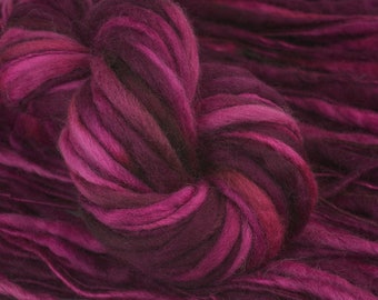 May include: A close-up of a deep purple and pink yarn with a variegated color pattern. The yarn is soft and fluffy, and it is perfect for knitting or crocheting.