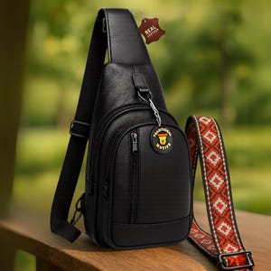 May include: Black leather crossbody bag with a zippered pocket and a strap with a traditional pattern. The bag has a small tag that says "Real Leather".