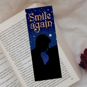 May include: A blue and black bookmark with a pixelated silhouette of a person with the text "Smile again" in orange.