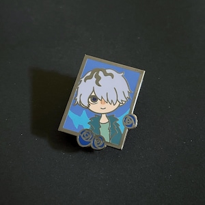 以下が含まれることがあります： 水色の髪と緑色のジャケットを着た漫画のキャラクターが特徴の長方形のエナメルピン。キャラクターは、青い背景に青い花のアクセントが施されています。ピンにはシルバーの縁取りがあります。