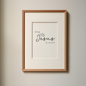 Può includere: Una stampa incorniciata con il testo "King Jesus is alive" in lettere nere con una corona sopra la parola "Jesus".