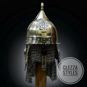 May include: A vintage-style metal helmet with a domed crown and ornate detailing. The helmet has a chainmail neck protector and a decorative central plate. The image includes the text "GLEZZA STYLES" within a circular logo.