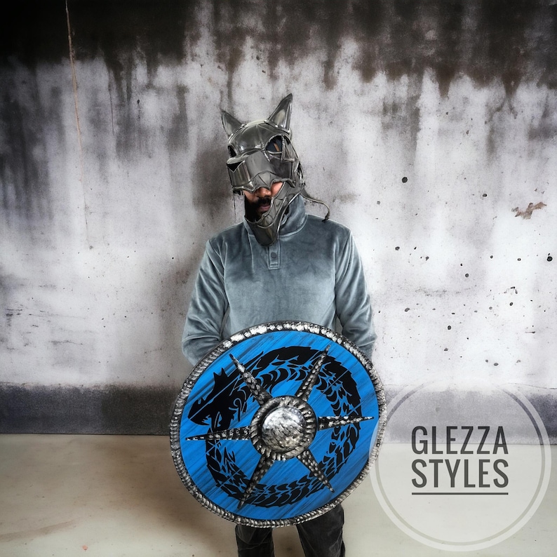 May include: A person wearing a wolf-themed helmet and holding a round shield. The shield has a blue background with a black dragon design and a silver center. The image includes the text "GLEZZA STYLES".
