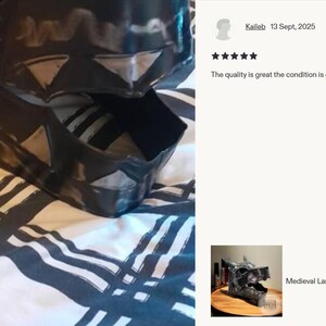 May include: A black, wolf-shaped medieval LARP helmet made of blackened 18-gauge steel. The helmet is detailed with angular features and sits on a patterned fabric. The image includes a customer review.