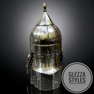 May include: A silver medieval helmet with a chainmail neck guard. The helmet features a rounded top with a pointed finial and is decorated with rivets and metal detailing. The image includes the text "GLEZZA STYLES" within a circular logo.