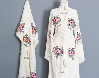 May include: A white cotton robe with a long-sleeved design and a tie belt. The robe features a repeating pattern of colorful eyes. The text "Babada Home" is printed on the robe.
