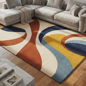 A colorful hand tufted abstract rug placed in a modern living room with light gray color sofa. the rug color is yellow, beige, blue and terracotta. the rug is placed on a wooden flooring. the rug size is 8x10 perspective to the room size.