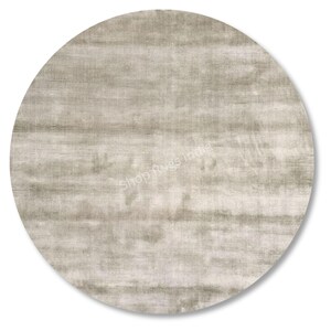 May include: A round, neutral-toned rug with a textured surface. The rug has a soft, muted color palette, with horizontal striations creating a subtle pattern. The text "Shop Rugs India" is visible on the rug's surface.
