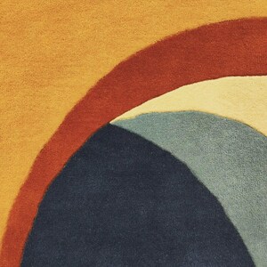 May include: A textured rug featuring a series of curved, overlapping bands in shades of mustard yellow, deep terracotta red, cream, and muted sage green, anchored by a large, dark navy blue semi-circular shape at the bottom of the composition.