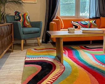 May include: A rectangular area rug featuring a vibrant, multi-colored pattern of wavy, organic lines in shades of red, orange, yellow, teal, blue, and black. The rug has a textured, tufted surface with varying pile heights that create a dimensional effect.