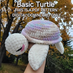 Puede incluir: Un juguete de amigurumi de tortuga tejido a crochet con una concha blanca y una concha morada, rosa y azul. El juguete está siendo sostenido por una mano frente a un fondo borroso de follaje otoñal. El texto "Basic Turtle" y "This is a PDF pattern" es visible en la parte superior de la imagen. El texto "Digital Download Only" es visible debajo del texto.
