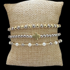 May include: A white ceramic mug with a black handle and the text "But First, Coffee" in a black, handwritten-style font. The mug is on a white surface.