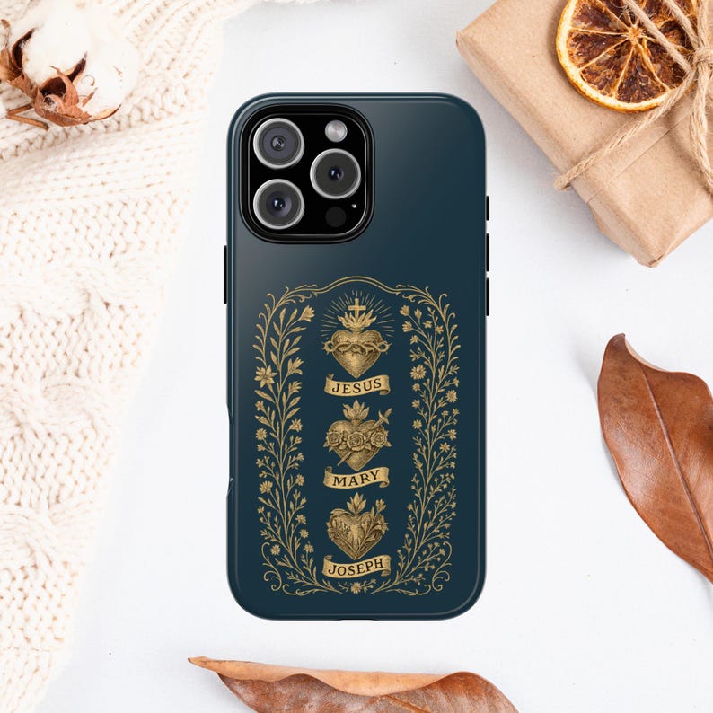May include: A dark teal phone case featuring a gold floral design with the words "JESUS", "MARY", and "JOSEPH". The case has a glossy finish and a camera cutout.