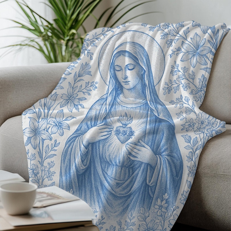 May include: A blue and white throw blanket featuring a floral design and an image of the Virgin Mary holding a heart with thorns.