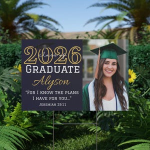 Peut inclure: Panneau de jardin de remise de diplôme avec le texte "2026 Graduate Alyson" en lettres dorées et blanches. Le panneau comprend une photo d'une diplômée souriante en chapeau et toge, et le verset biblique Jérémie 29:11.
