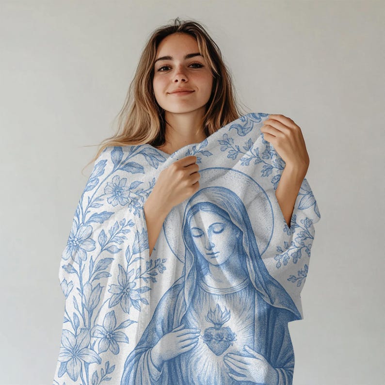 May include: A white throw blanket with a blue floral pattern and a blue image of the Virgin Mary holding a heart. The blanket is made of soft, comfortable fabric.