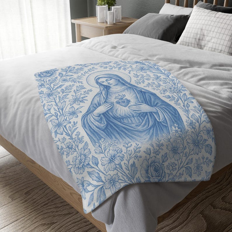 May include: A blue and white throw blanket featuring a floral design and an image of the Virgin Mary holding a heart.
