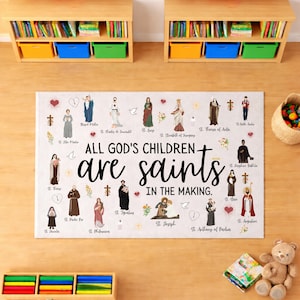 May include: A rectangular rug with the text "ALL GOD'S CHILDREN are saints IN THE MAKING." The rug features illustrations of saints and religious symbols in a colorful design. The rug is on a wooden surface.