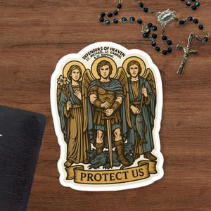 May include: A sticker depicting three angels with halos, holding a flower, sword, and fish. The sticker has the text "DEFENDERS OF HEAVEN ST. MICHAEL, ST. GABRIEL & ST. RAPHAEL PROTECT US". The sticker is on a wooden surface.