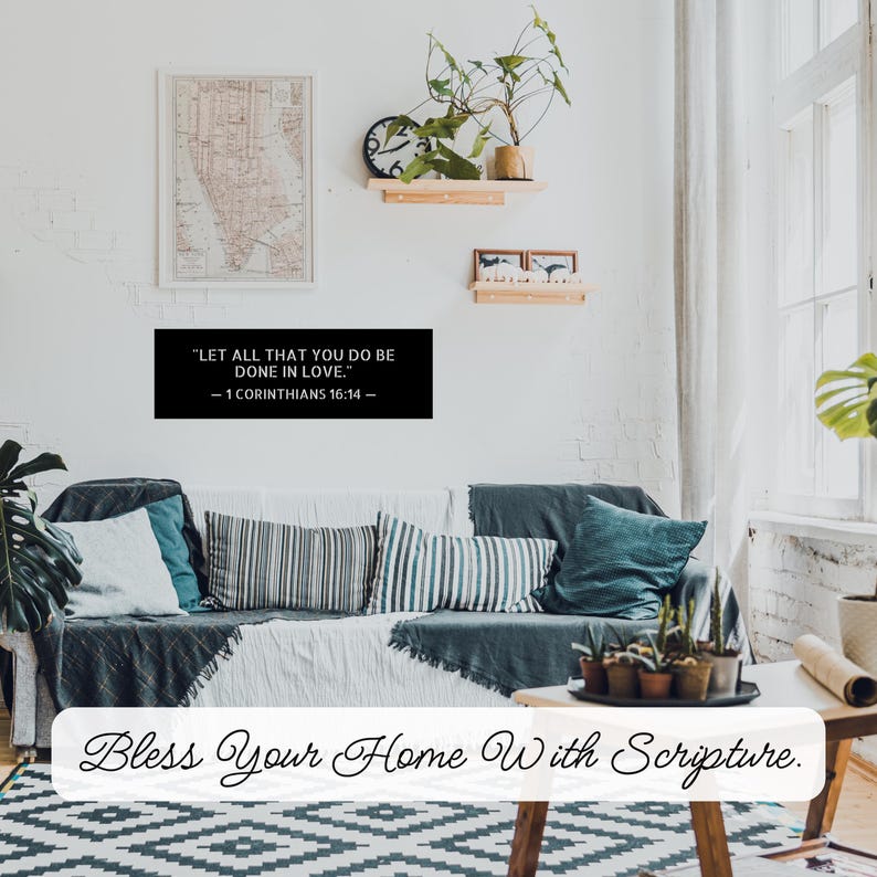 Op de afbeelding: Een woonkamer met een bank, kussens en decoratieve items. Een zwart bord toont de tekst "LET ALL THAT YOU DO BE DONE IN LOVE. - 1 CORINTHIANS 16:14 -" boven de bank. De woorden "Bless Your Home With Scripture" staan onderaan.