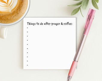 May include: A white notepad with the text "Things to do after prayer & coffee:" is next to a pink pen and a cup of coffee with latte art. A sprig of green leaves is also in the image.