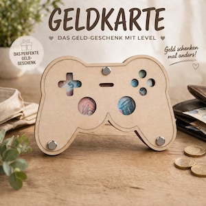 Könnte beinhalten: Eine Holz-Controller-förmige Geldgeschenkbox mit dem deutschen Text "GELDKARTE" oben. Die Box hat Aussparungen für Geld und ist mit silbernen Nieten verziert. Der Text "DAS GELD-GESCHENK MIT LEVEL" ist ebenfalls sichtbar.