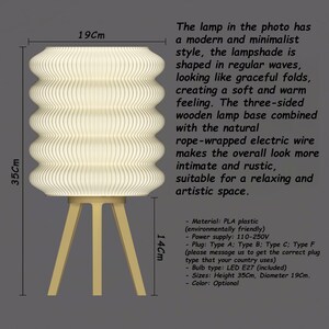 K&ouml;nnte beinhalten: Moderne Tischlampe im minimalistischen Design. Der Lampenschirm, 35 cm hoch und 19 cm im Durchmesser, weist ein wellenartiges Muster auf. Er steht auf einem dreibeinigen Holzsockel mit einem seilumwickelten Elektrokabel. Die Lampe ist f&uuml;r einen entspannten Raum geeignet.