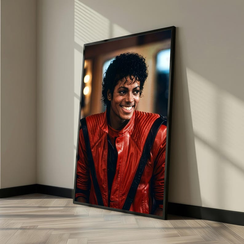May include: Framed portrait of a smiling person with dark curly hair, wearing a red leather jacket with black accents. The portrait is displayed in a black frame, leaning against a wall.