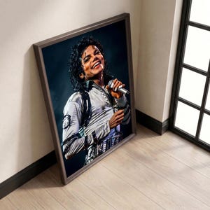 May include: Framed portrait of Michael Jackson in a silver jacket, smiling and holding a microphone. The image is in a brown frame, leaning against a white wall and wooden floor.