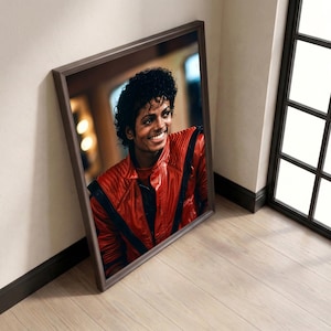 May include: Framed portrait of a smiling man in a red leather jacket with black accents. The portrait is in a brown frame and leans against a wall. The man has dark curly hair.