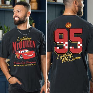 May include: Black t-shirt featuring Lightning McQueen graphics. The front displays "Lightning McQueen" with a red race car and "Piston Cup Champion." The back shows a large "95" and "Lightning McQueen" in gold.