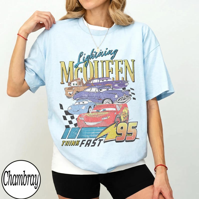 Puede incluir: Camiseta azul claro con un gr&aacute;fico de Rayo McQueen y otros personajes de Cars. El dise&ntilde;o incluye el texto "Lightning McQueen", "95" y "Think Fast". La camiseta tiene mangas cortas y cuello redondo.