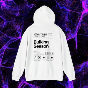 Peut inclure: Sweat-shirt à capuche blanc avec un imprimé graphique noir qui dit "100% Tren Natty Free Bulking Season". Le graphique est conçu pour ressembler à une étiquette de produit avec une liste d'ingrédients et d'instructions.