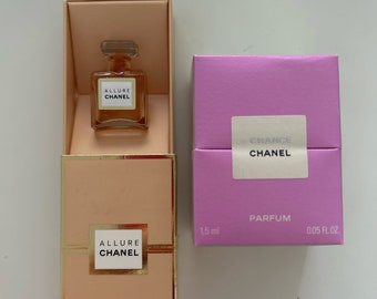 May include: Two small perfume bottles in their boxes. The boxes are both peach colored with gold trim. The bottles are clear glass with gold caps. The left box has the text "Allure Chanel Parfum 1.5 ml 0.05 fl.oz." The right box has the text "Chance Chanel Parfum 1.5 ml 0.05 fl.oz."