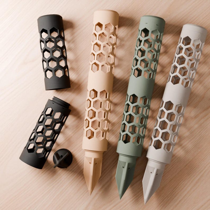 May include: A collection of cylindrical plant support stakes featuring a repeating hexagonal cutout pattern. The set includes three long stakes in beige, sage green, and light gray, plus two shorter black segments and a small black circular cap.