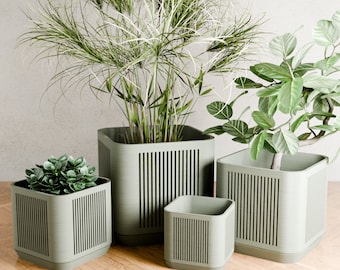 May include: Four green planter pots with different sized plants. The pots have a vertical slatted design.