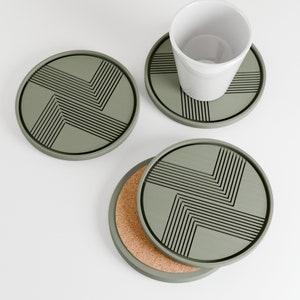 May include: Set of four green coasters with a geometric pattern. Two coasters are stacked on top of each other, and one coaster has a cork backing.