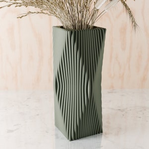 May include: A green ceramic vase with a unique, textured, wavy design. The vase is empty and ready to hold flowers.