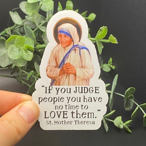 Puede incluir: Una pegatina blanca con una cita de la Madre Teresa. La cita dice: "Si JUZGAS a las personas, no tienes tiempo de AMARLAS." La pegatina presenta un retrato de la Madre Teresa.