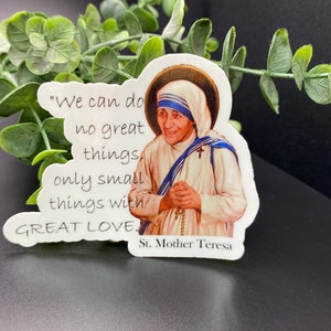 Puede incluir: Una pegatina blanca con una cita de la Madre Teresa: "No podemos hacer grandes cosas, solo peque&ntilde;as cosas con GRAN AMOR." La pegatina presenta un retrato de la Madre Teresa con un h&aacute;bito blanco y una faja azul.