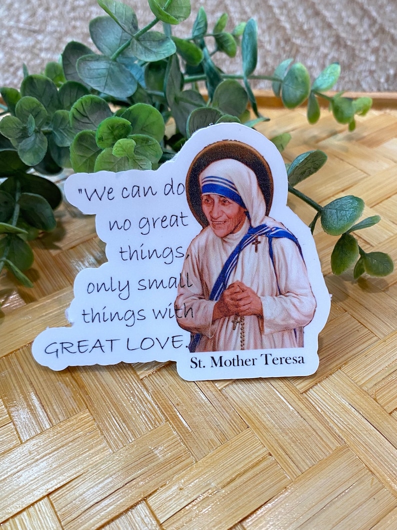 Puede incluir: Pegatina blanca con una cita de la Madre Teresa: "No podemos hacer grandes cosas, solo peque&ntilde;as cosas con GRAN AMOR." La pegatina presenta una imagen a color de la Madre Teresa.