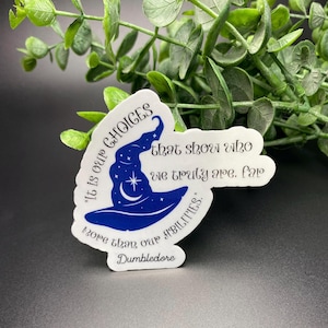May include: A white sticker with a blue wizard hat and stars. The sticker has a quote from Dumbledore: "It is our choices that show who we truly are, far more than our abilities."