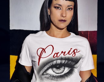 Maglietta con grafica parigina, motivo a occhio, capo alla moda ispirato allo street style, abbigliamento casual, cotone bianco, tessuto morbido, look trendy urbano