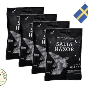 Op de afbeelding: Vier zakjes vegane drop met de tekst "Salta Häxor" en "Salt for the Wicked" op de voorkant. De zakjes zijn zwart met witte tekst en een heks-afbeelding. Elk zakje is 100g.