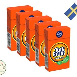 Könnte beinhalten: Eine Packung mit fünf orangenen Schachteln Fazer Tutti Frutti Original Süßwaren. Die Schachteln sind übereinander gestapelt. Die Schachteln haben ein weißes Etikett mit dem Fazer-Logo und dem Text "Tutti Frutti Original" in einem weißen Kreis. Die Schachteln sind gelatinefrei und haben natürliche Farben und Aromen.