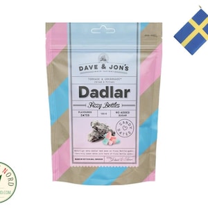 Könnte beinhalten: Eine rosa, blaue und braune Tüte mit Dave & Jon's Dadlar Fizzy Bottles, einem Dattel-Snack mit Bonbonüberzug. Die Tüte hat ein rosa-blaues Streifenmuster mit dem Markennamen und dem Produktnamen in schwarzer Schrift. Die Tüte enthält außerdem den Text "Geschmackte Datteln" und "Ohne Zuckerzusatz".