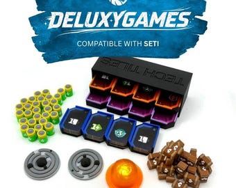 Könnte beinhalten: Ein Brettspiel-Zubehörset mit einem schwarzen Kartenorganizer mit der Aufschrift TECH TILES, Stapeln bunter Spielkarten, zahlreichen kleinen grünen und gelben zylindrischen Spielsteinen, zwei grauen runden Scheiben und einer transparenten orangefarbenen Kuppel.