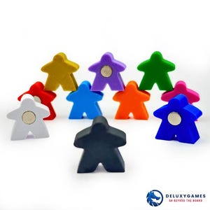 Puede incluir: Un conjunto de coloridas piezas de juego de madera en varios colores, incluyendo amarillo, morado, verde, naranja, rosa, azul, rojo, blanco y negro. Cada pieza tiene una forma única y un imán circular. Las piezas están dispuestas sobre un fondo blanco.