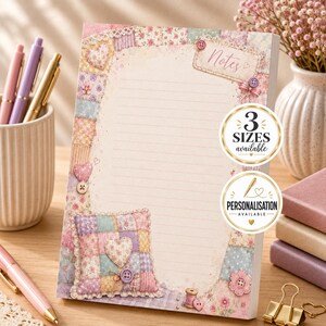 May include: A rectangular notepad with lined paper featuring a patchwork quilt border in pastel colours, including pink, blue, and yellow. The design includes illustrations of hearts, buttons, and lace. The text Notes is printed at the top right.